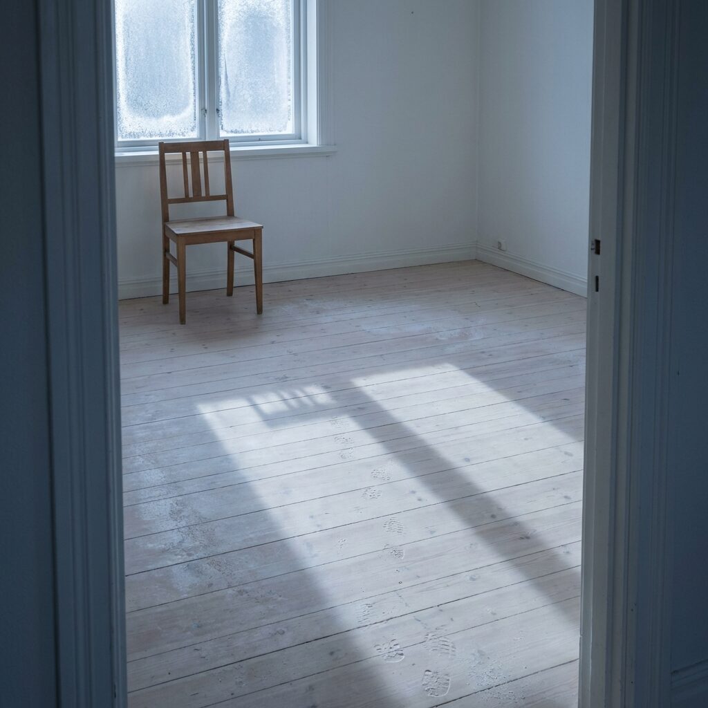 An empty Scandinavian house interior in winter light, seen through a doorway. Pale wooden floors, white walls, a single chair by a frost-covered window. Footprints visible in light dust on the floor leading away toward the door. Cold blue-grey natural light streams in, creating long shadows. The mood is melancholy and still, evoking absence and memory. Minimalist composition, muted Nordic color palette, square format, no text, no people.